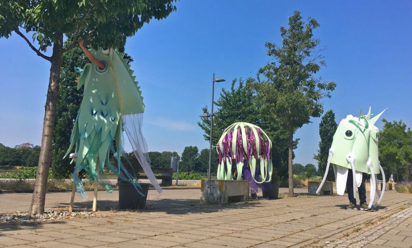 Drei bunte, phantasievolle Theaterfiguren, die von Menschen bewegt werden